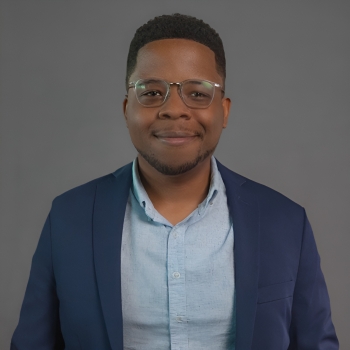 Portrait of black man with short hair wearing glasses, a dark blue blazer and a light blue button-down shirt