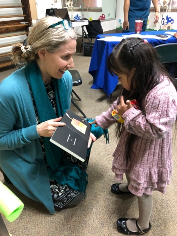 Victoria Clark kneeling down to work with a little girl