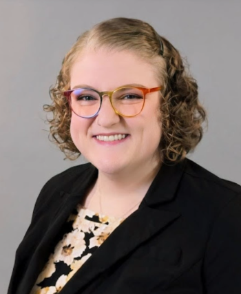 Portrait of a woman with short dark blonde hair and rainbow-colored classes