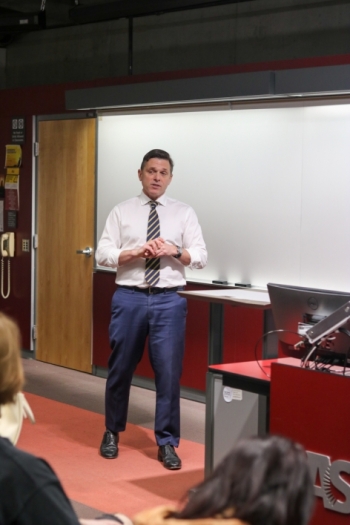 Foreign Service Officer Tom Wotka standing at the front of a classroom speaking.