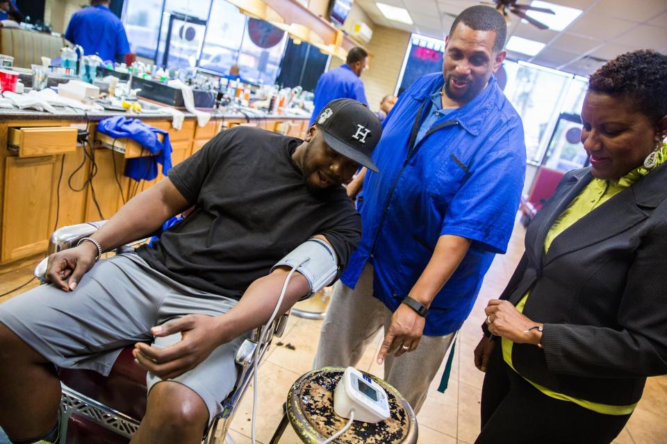 A man has his blood pressure taken at a barbershop.