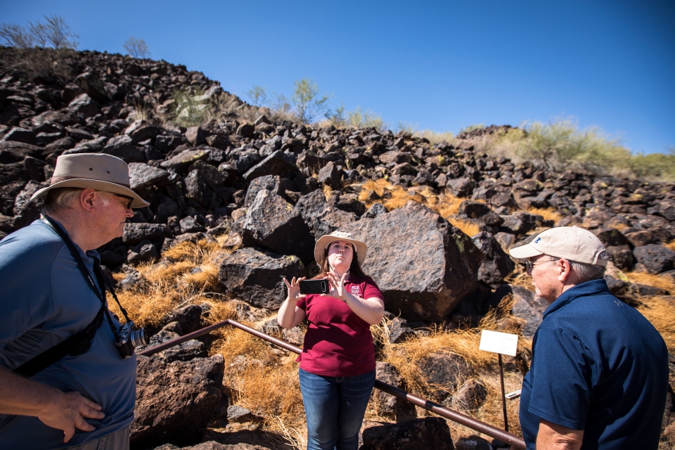 woman taking photo with cell phone at petroglyph reserve