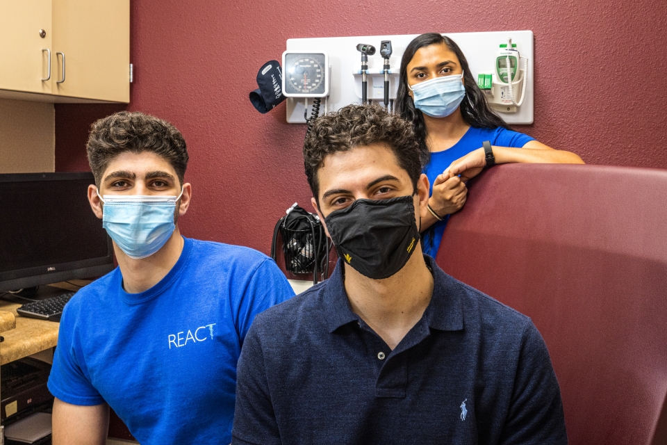three students wearing mask pose for photo in a medical exam room