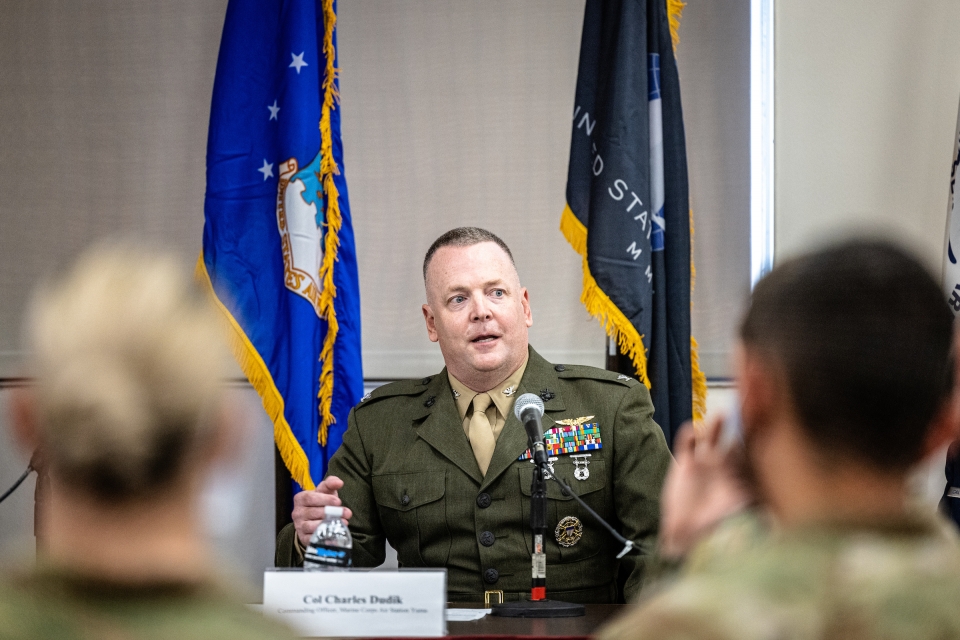 A man in a Marine Corps uniform speaks as part of a panel to a room full of audience members