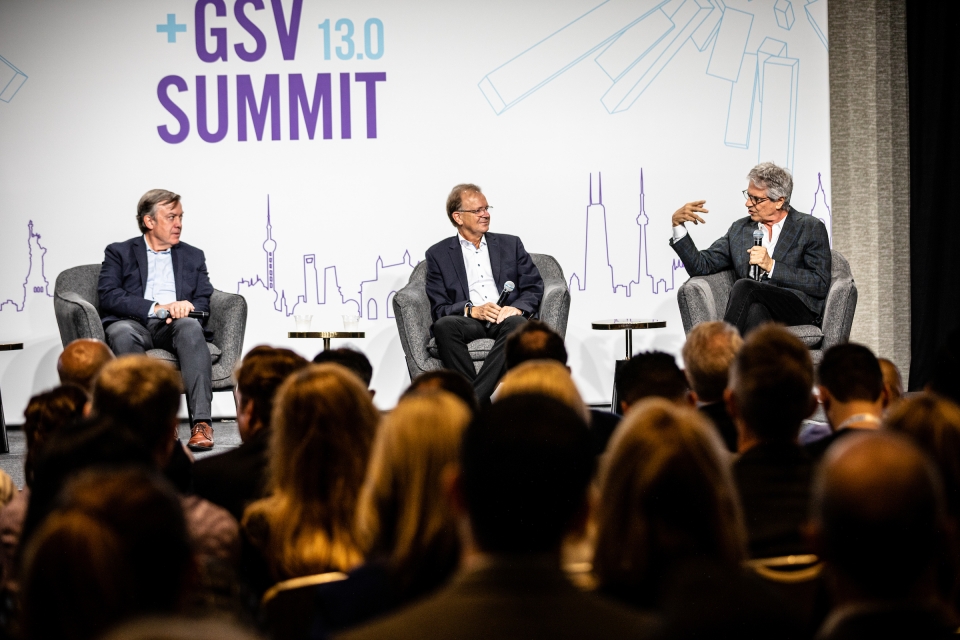 Three men on stage at ASU+GSV Summit in front of audience