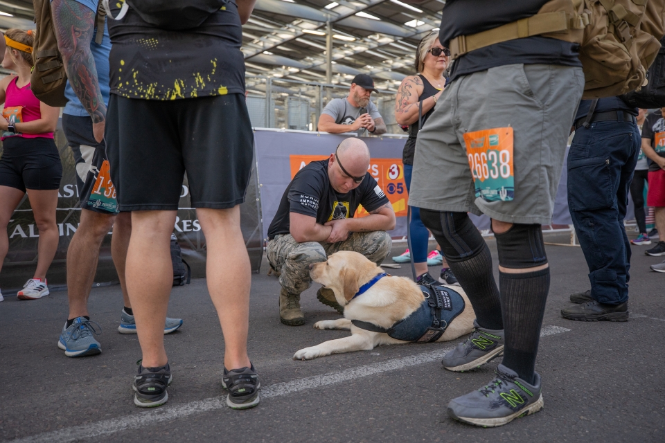 man kneeling on street with service dog before race