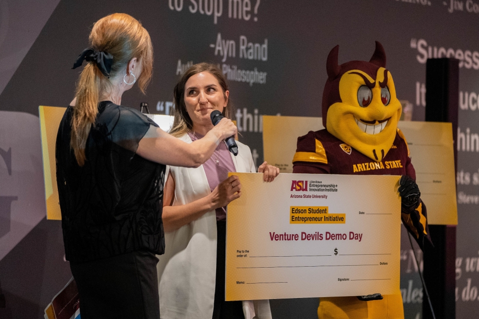 woman being presented with giant check with Sparky in the background