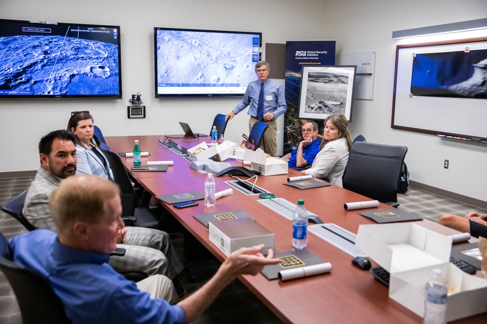 People sit around a conference table with lunar photos on the walls