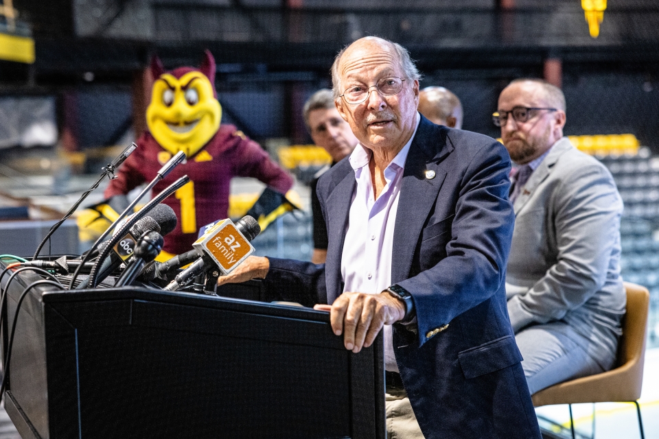 Man speaking at lectern with Sparky mascot in the background