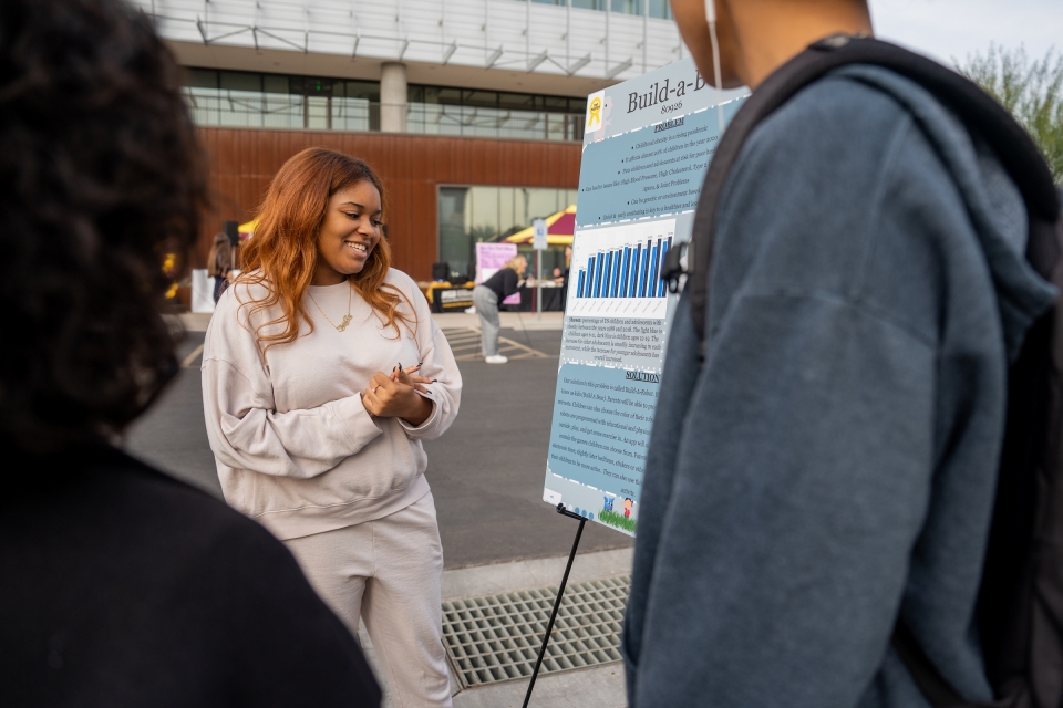 Woman talking to people about her poster presentation