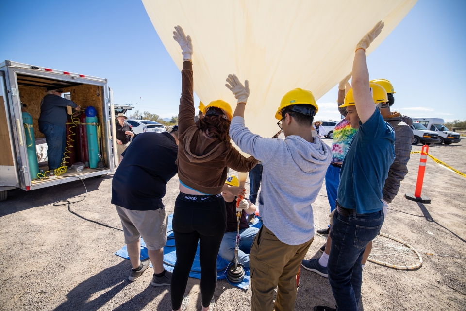 People holding large weather balloon up