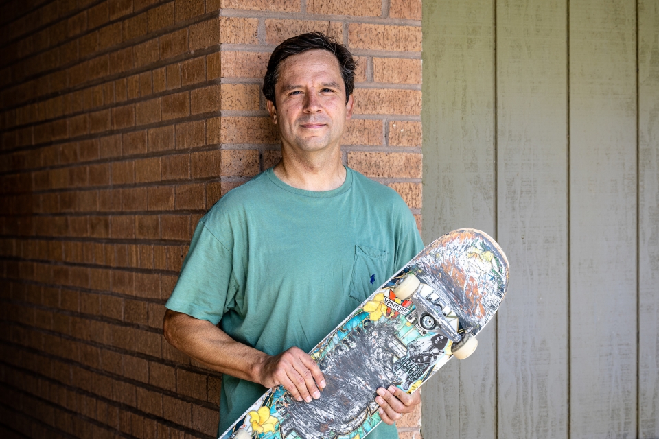 Man posing for portrait holding skateboard