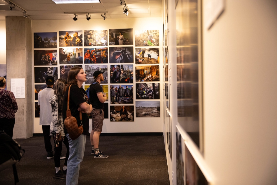 People look at walls filled with photos from the war in Ukraine