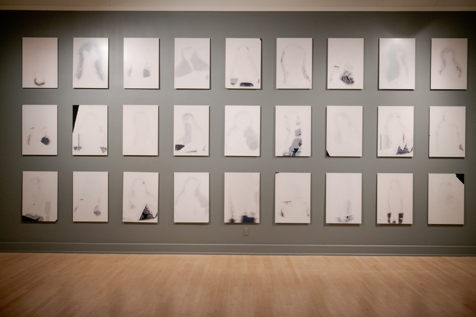 exhibit of many rectangular drawing lined up on a wall