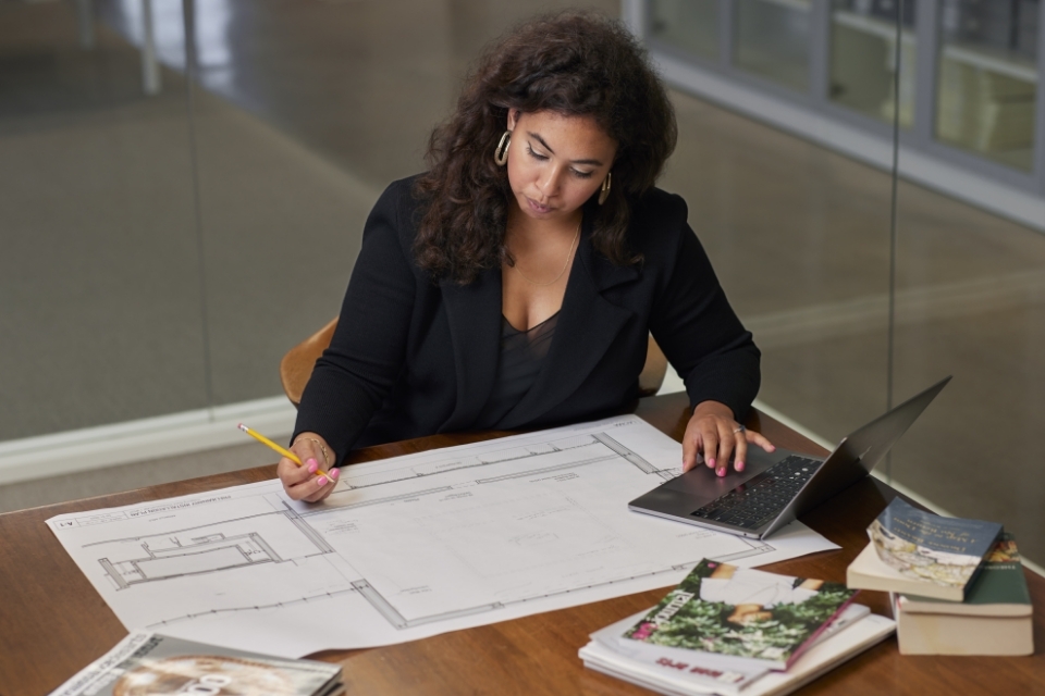 Woman working at desk looking at blueprint