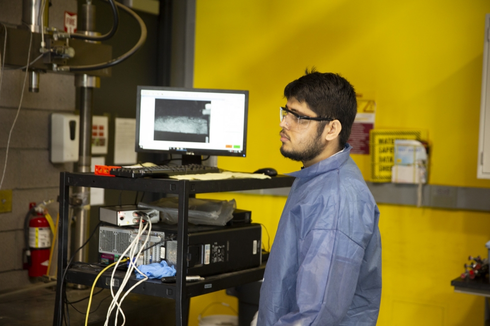 Ashutosh Maurya, a doctoral student at ASU, wears protective goggles and a jumpsuit while using imaging technology in a lab.