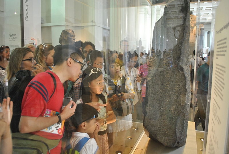 Image of tourists viewing the Rosetta Stone at the British Museum in London. ProtoplasmaKid / Wikimedia Commons / CC-BY-SA 4.0