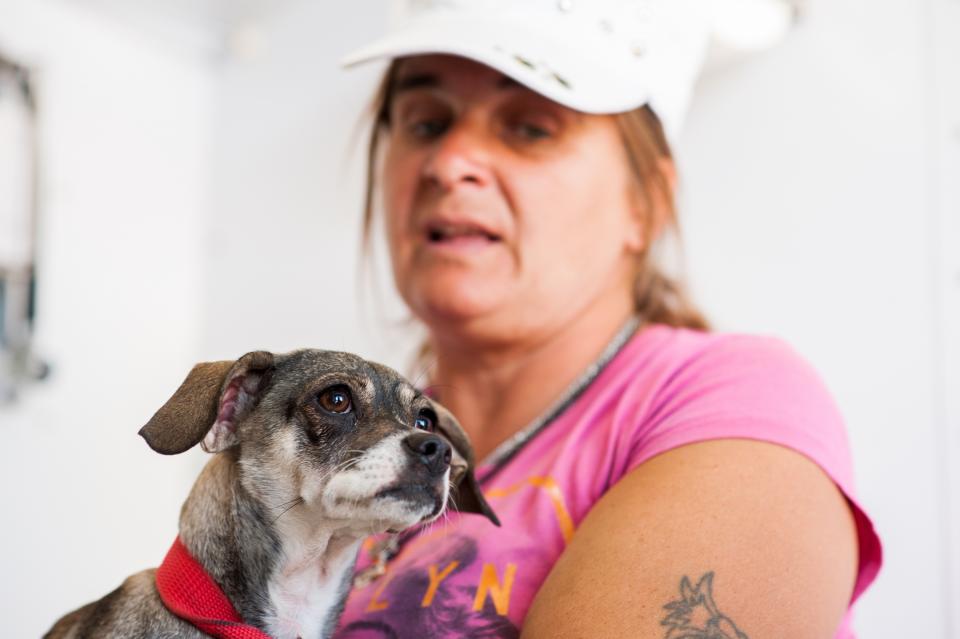 A woman holds her dog at a pet clinic.