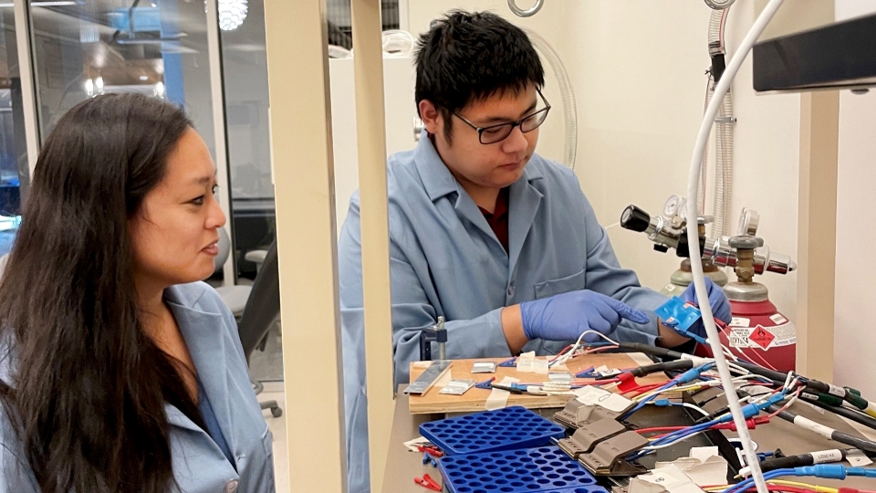 Candace Chan observes materials science and engineering doctoral student Jinzhao Guo as he connects a solid-state battery to testing equipment
