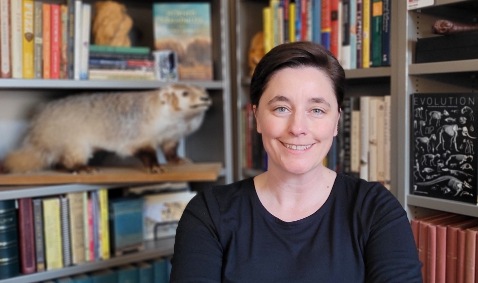 ASU Associate Professor Katie Hinde seated in front of book shelves.