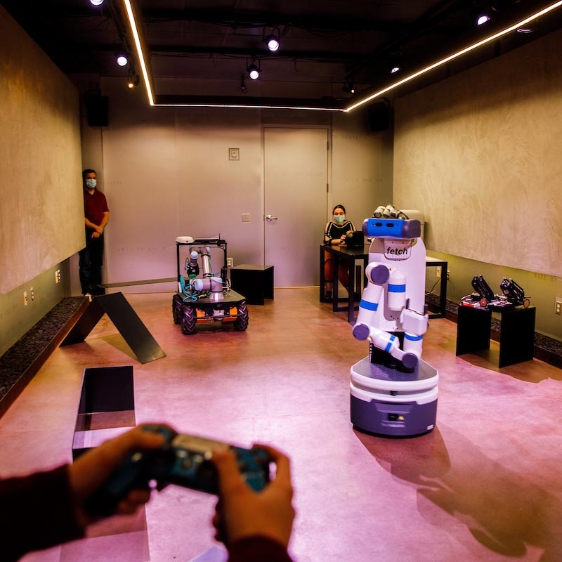 Three ASU researchers experiment with using two robots at an ASU lab. 