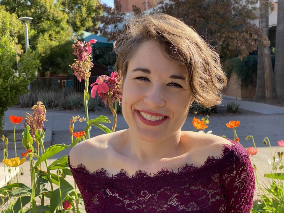 Portrait of researcher Karie Behm. Behm is photographed in an outdoor setting in front of flowers.