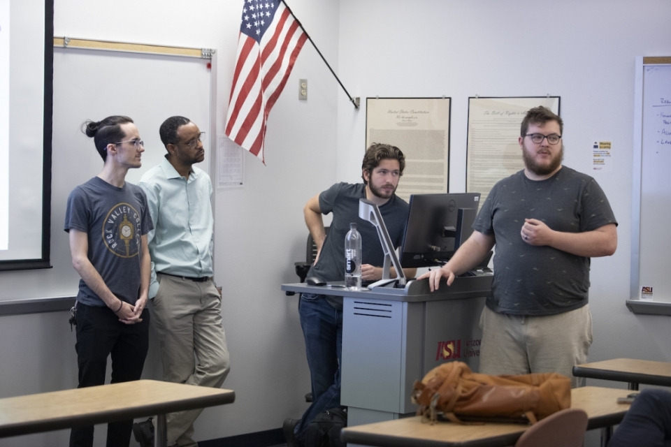 Four students at the front of a classroom giving a presentation.