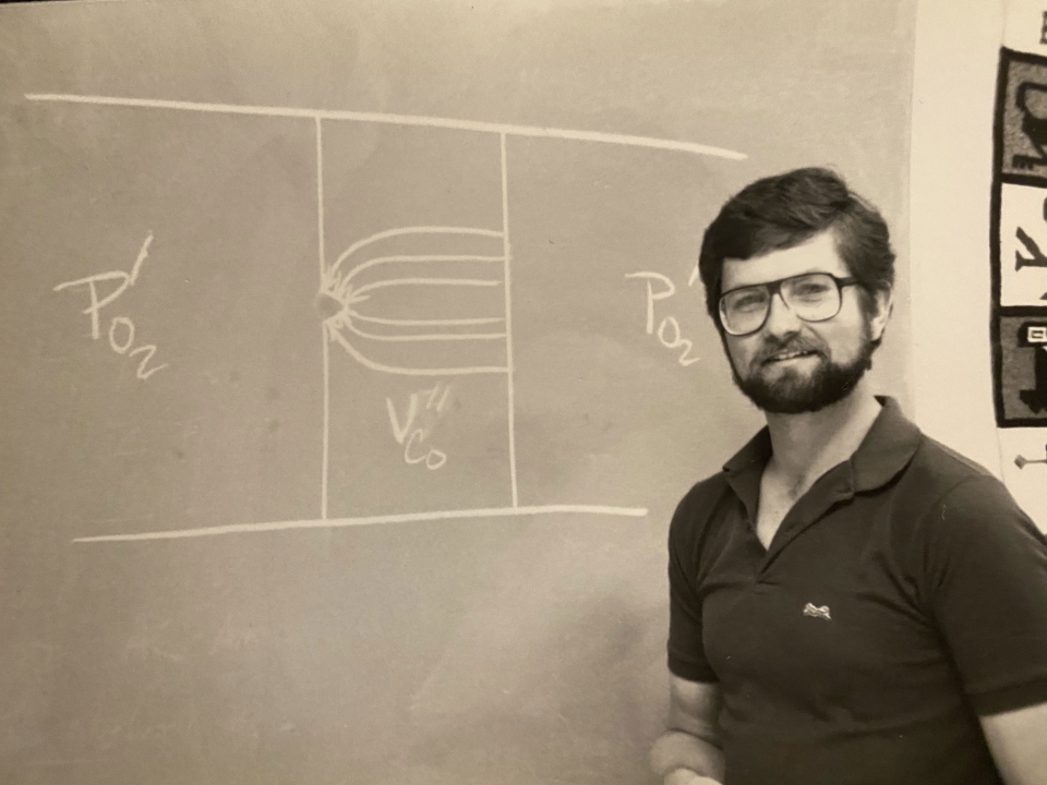 black and white photo of professor at a chalk board