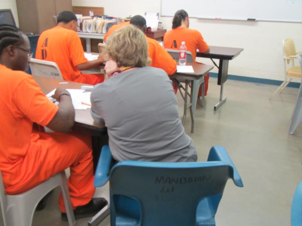 A woman tutors a classroom of inmates