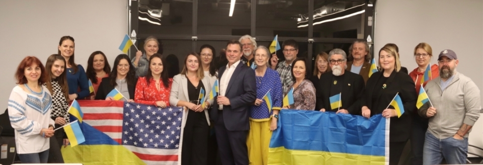 People posing for a group photo holding American and Ukranian flags.