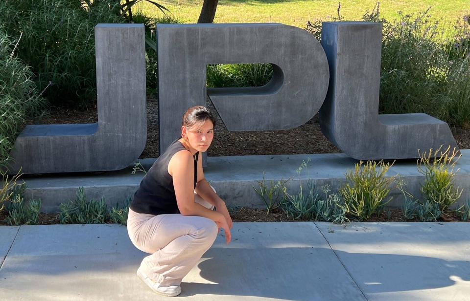 A woman poses in front of the JPL sign