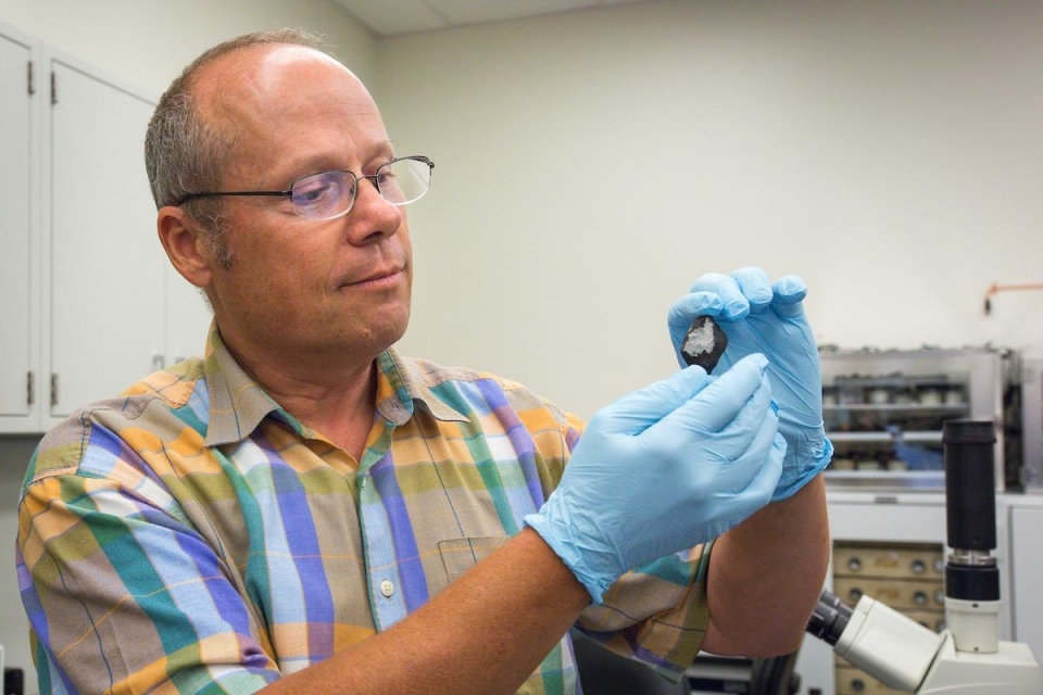 ASU Research Professor Laurence Garvie holding up a meteorite sample.
