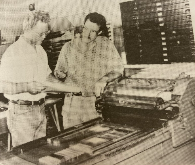 archived black and white photo of two people using letterpress