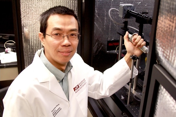 ASU researcher Shaopeng Wang smiling and wearing a white lab coat.