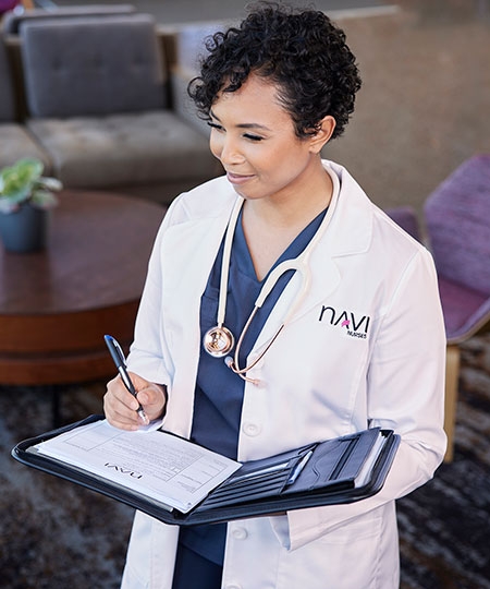 A nurse in a lab coat writes in a folder