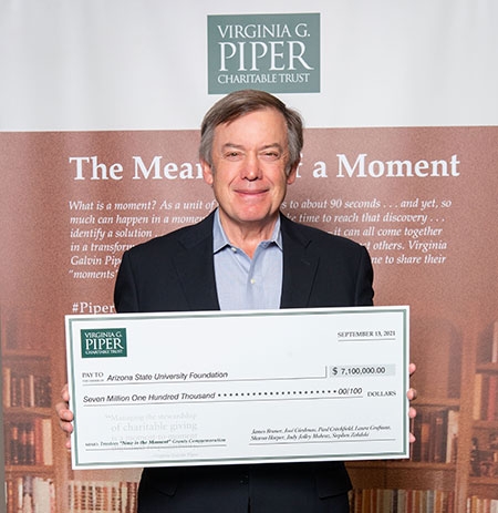 ASU President Michael Crow holding an oversized check.