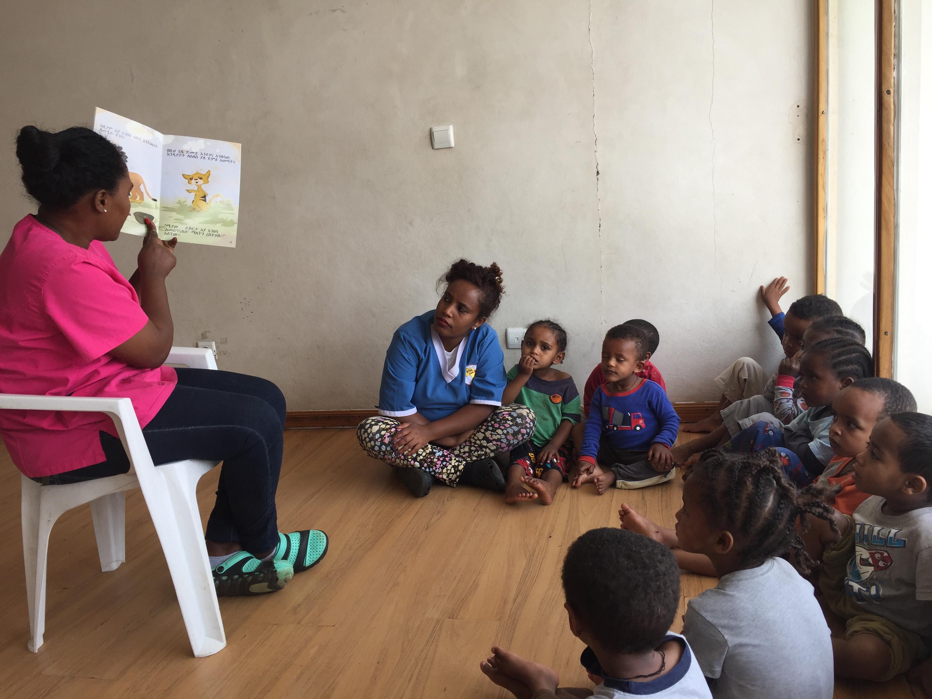 Teacher reading a book to a small group of children in and Ethiopian classroom.