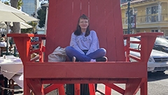 Young woman sitting in an oversized red wooden chair