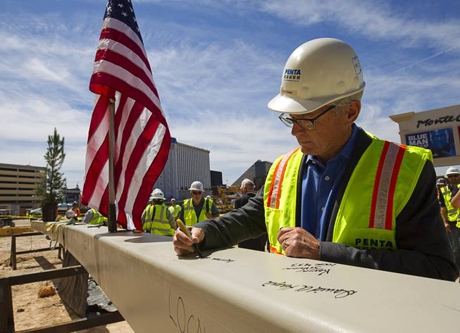 Jeffrey Ehret, a founding partner of The PENTA Building Group, wearing a hard hat at a construction site as he signs a large beam.