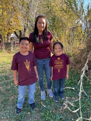 Native American woman and her two sons smiling in a wooded setting.