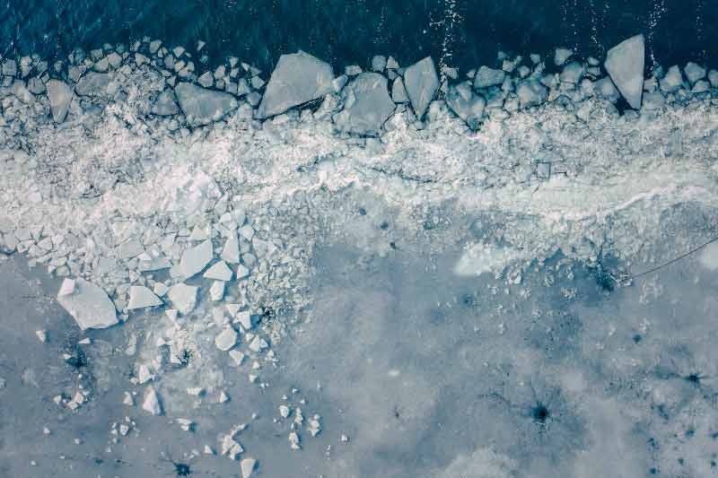 aerial view of sea ice breaking off of glacier into ocean