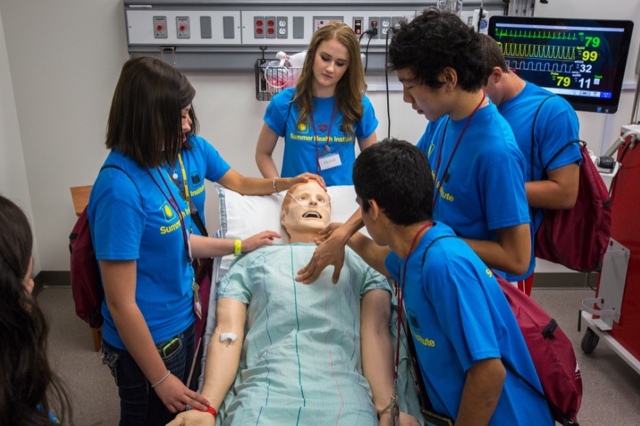 students gather around a medical manikin at ASU Summer Health Institute