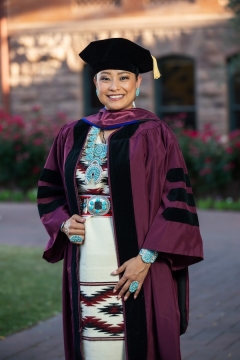 Portrait of ASU graduate Brianne Arviso in her cap and gown and traditional Navajo dress.