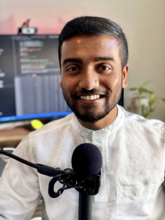 Portrait of ASU PhD student and researcher Jay Shah with a microphone.