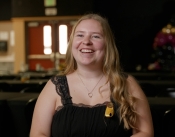 Edson College BSN Graduate Ainsley Pape is pictured smiling in a black sleeveless top with a nurisng pin visible