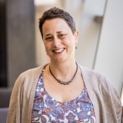 ASU News photo of Manushag Powell by Charlie Leight. Powell wears a patterned top and a sweater while she stands in the main foyer of Ross-Blakley Hall.