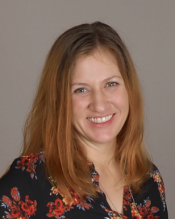 Portrait of a woman with medium length reddish-brown hair wearing a floral blouse