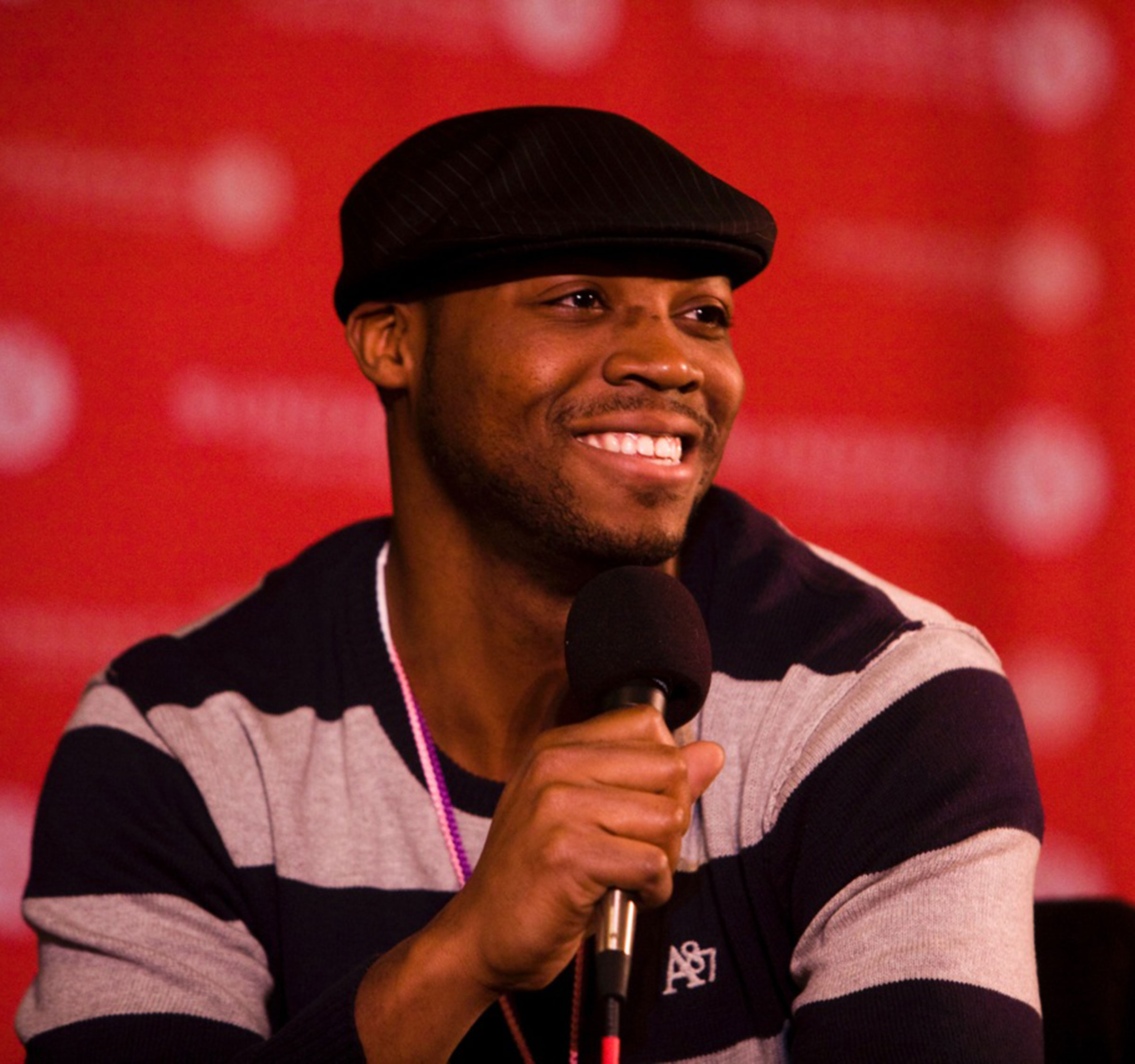  speaks into a microphone while smiling on a film festival stage