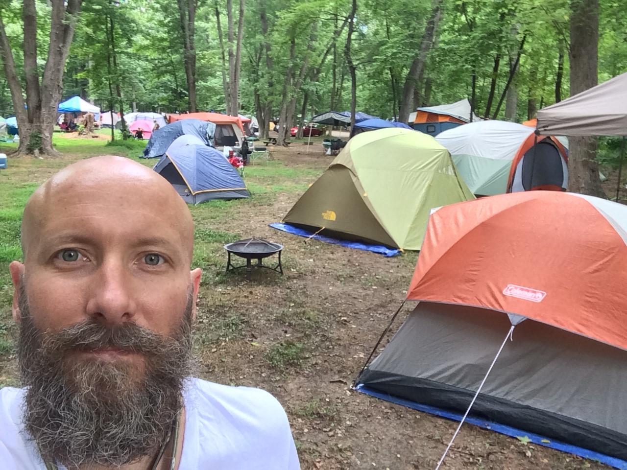 selfie of man in woods with tents