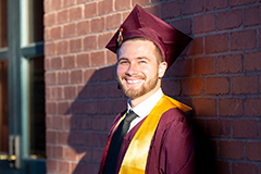 man posing in graduation cap and gown